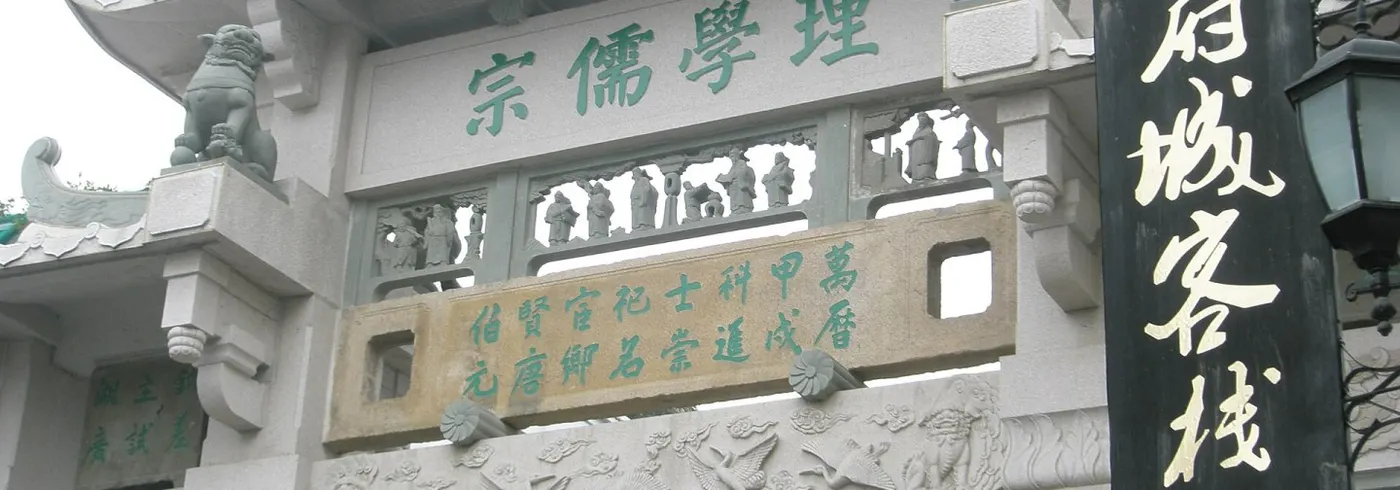 石牌坊:绿瓦飞檐下刻「理學儒宗」,梁上立石狮,右侧悬「府城客棧」招牌