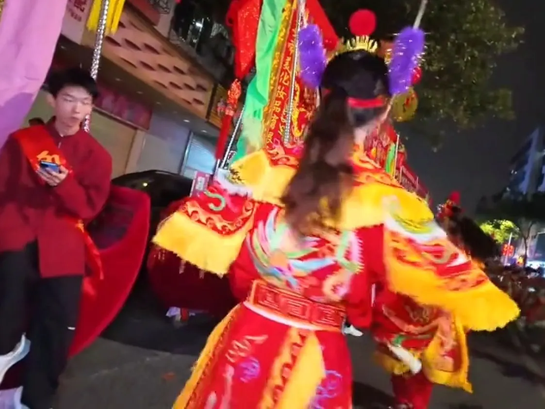 一名隊員頭戴花冠,紅綠戲服,雙手上舉