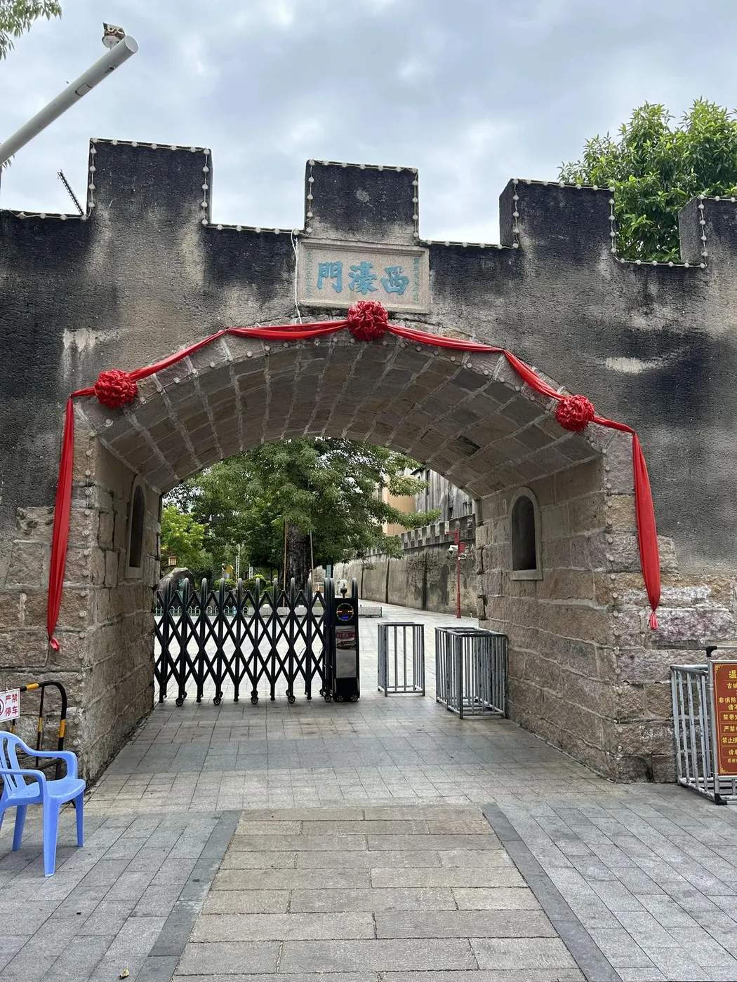 石砌门洞与城垛，门额题「西濠门」，门上系红绸