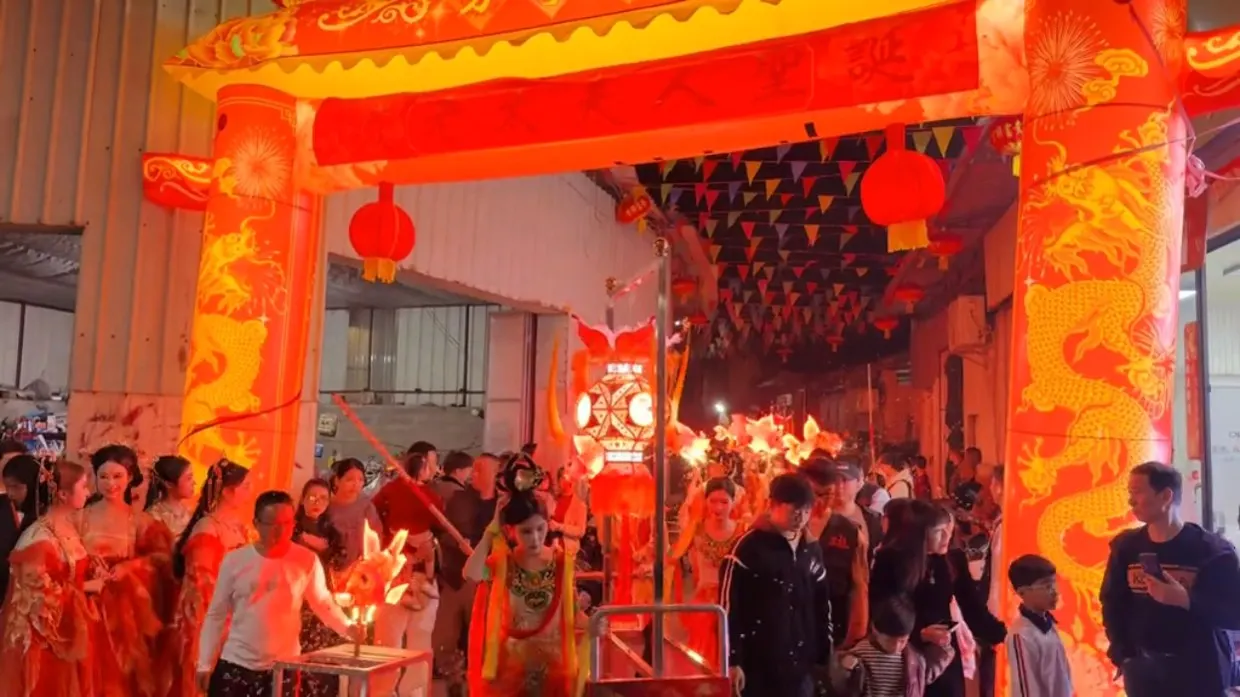 花灯阵前的游行队伍:花灯挂在灯架上,队伍提灯而过。
