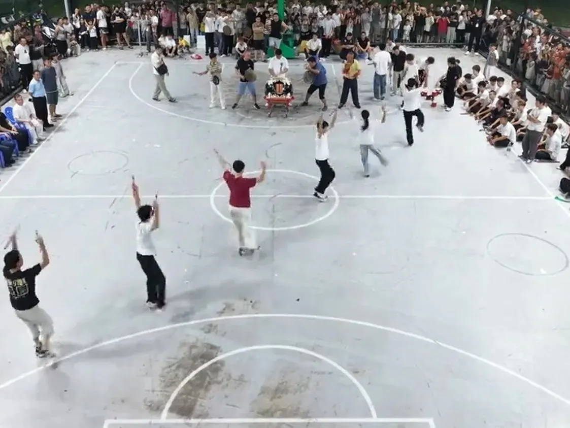 籃球場上幾名隊員把雙槌舉過頭頂，圍欄外站滿看的人