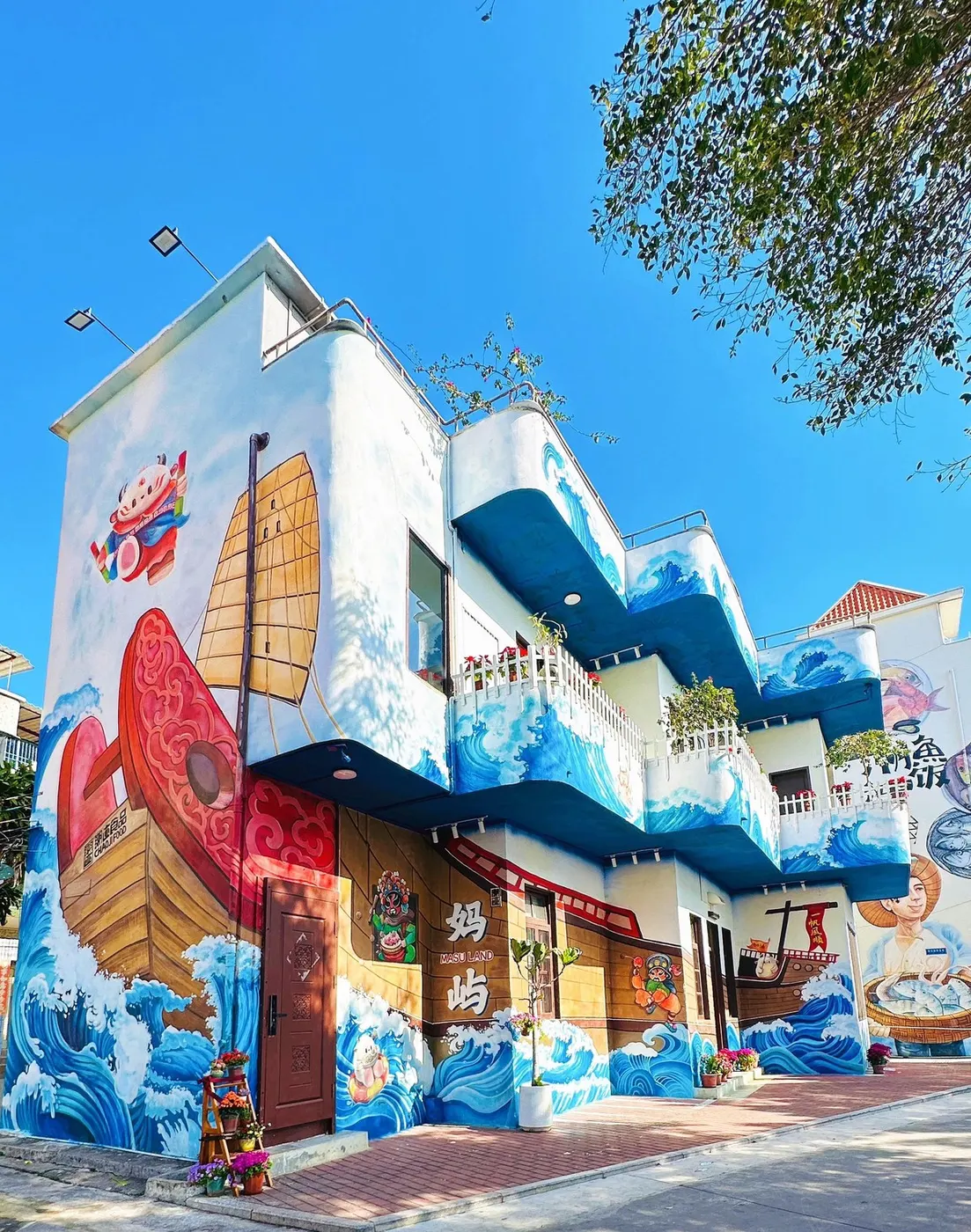 临街楼房整面画满海浪与鱼,屋前停着摩托