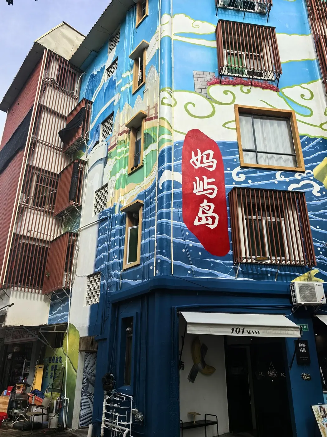 蓝底竖招牌写「妈屿岛」,背后是彩绘墙面