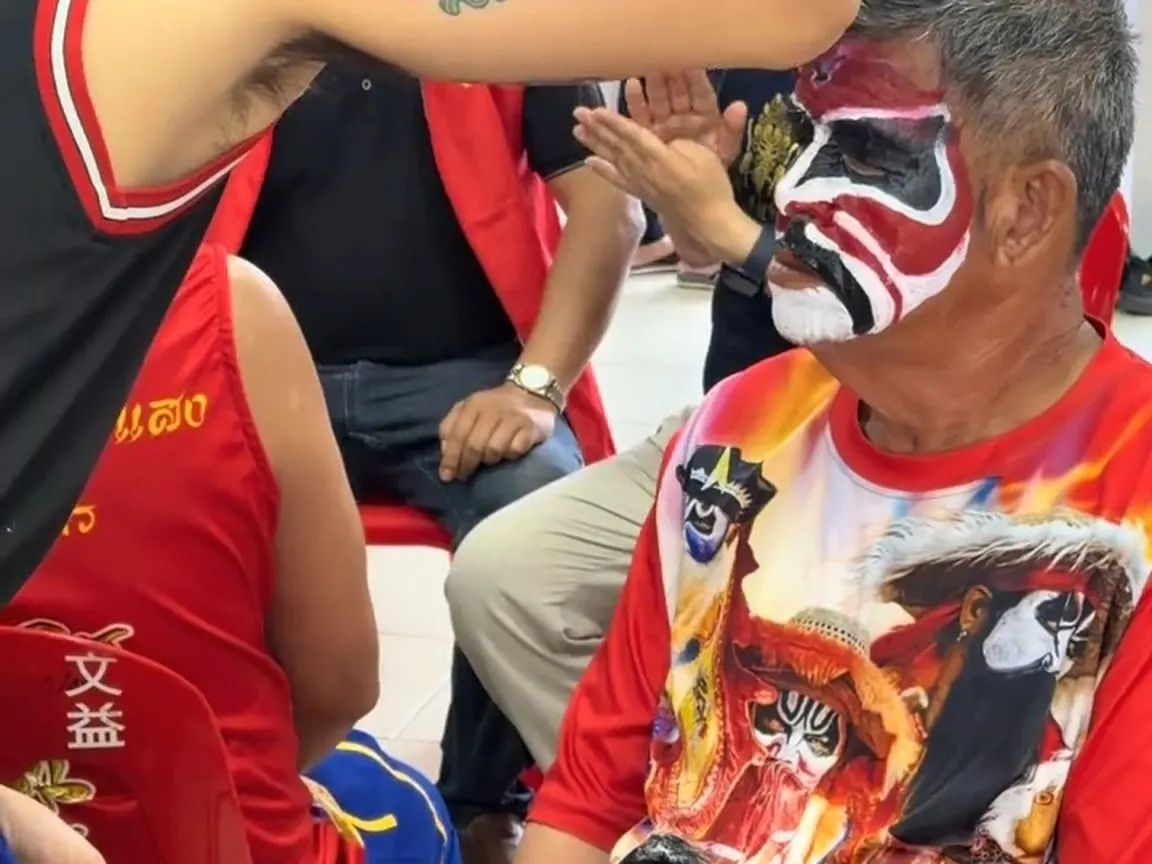 畫好臉的人坐在紅塑膠椅上等上場，身上的 T 恤也印著臉譜