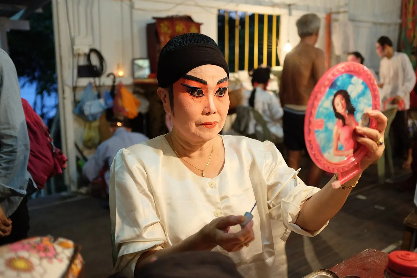 潮剧演员在后台对镜补妆,已勾好脸谱