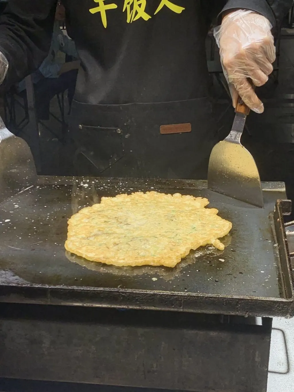 平底锅上摊开的蚝烙，正在两面翻煎