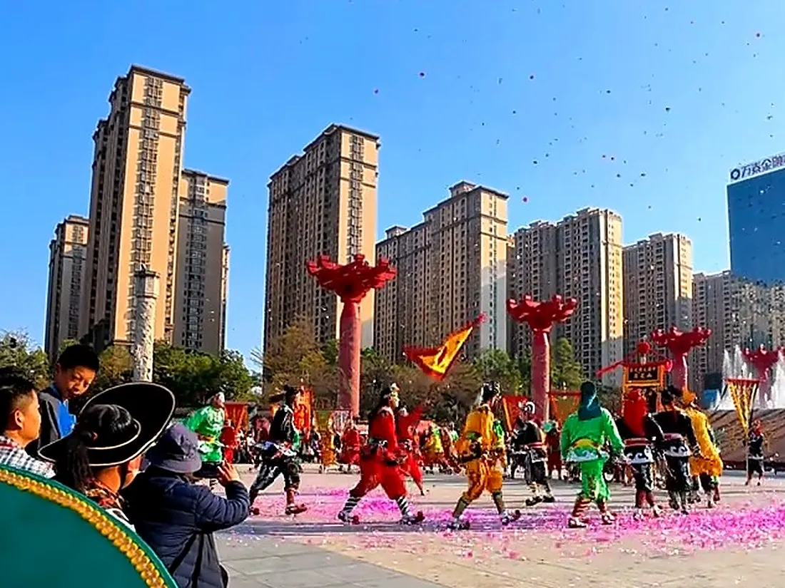 队伍在广场散开，地上落着炮仗纸屑