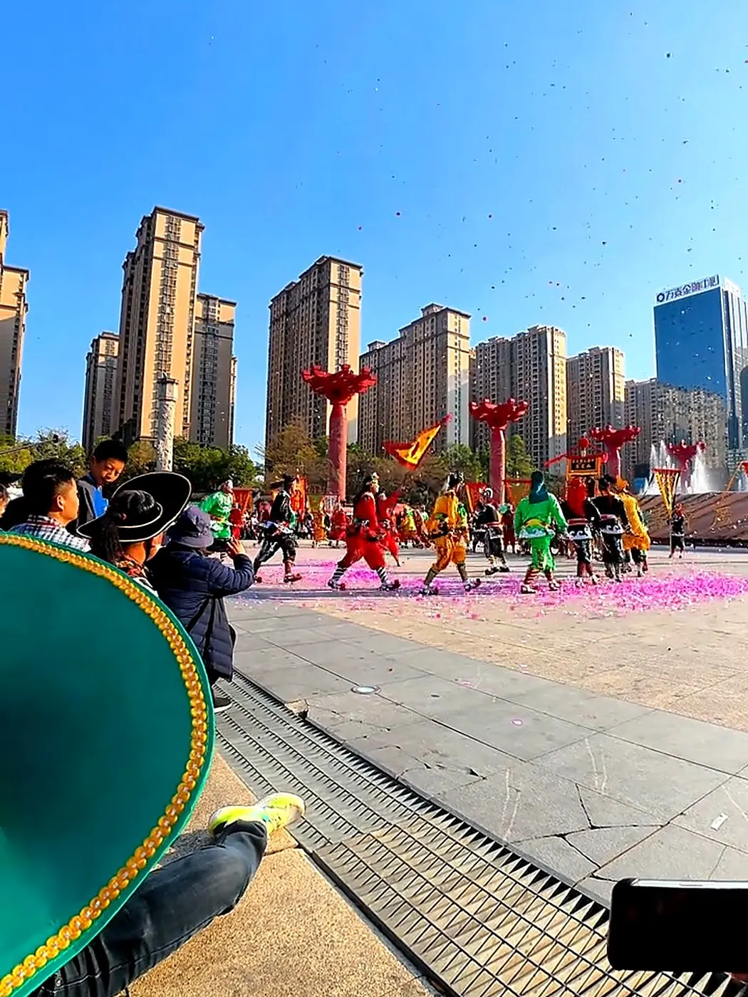 普宁英歌队在场地上列队展开，地上落着炮仗纸屑