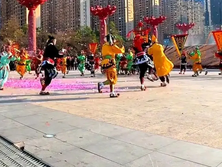 广场上队员散开，红柱彩纸，背景是成排高楼
