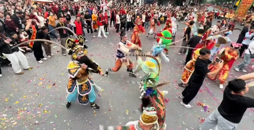 街心兩名隊員騰身對擊，長雉尾相交，地上鋪一層彩色紙屑
