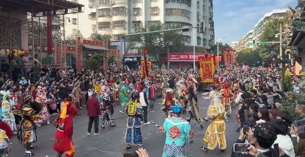 街口立著牌樓與紅色橫幅，隊伍從牌樓下經過，兩側站滿觀眾