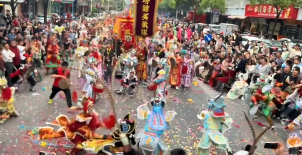 街面上一排隊員列開對擊，高處掛著寫有隊名的豎幡，地上鋪滿彩色紙屑
