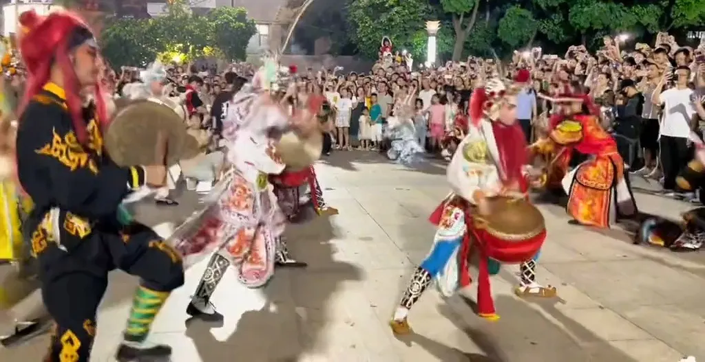 广场上三名队员，一人执大钹、两人各执小鼓