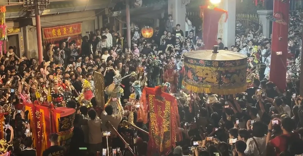 夜裡的廟門前，一面彩繪大鼓架在人堆裡，兩旁立著紅旗