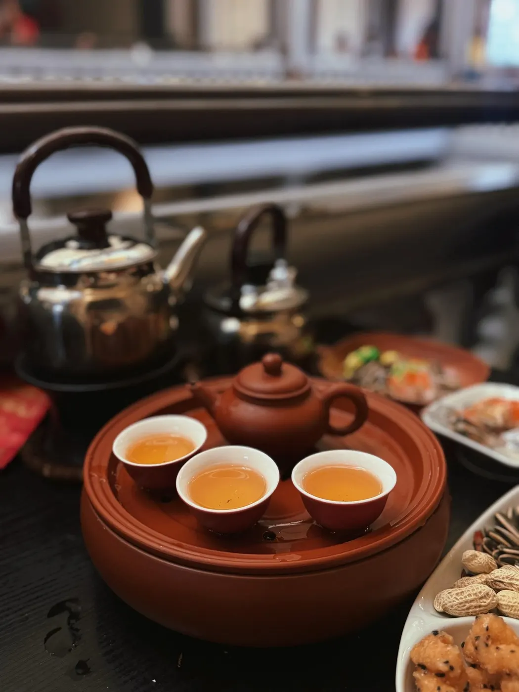 壶、三只茶杯与茶托摆在木桌上,背景虚化