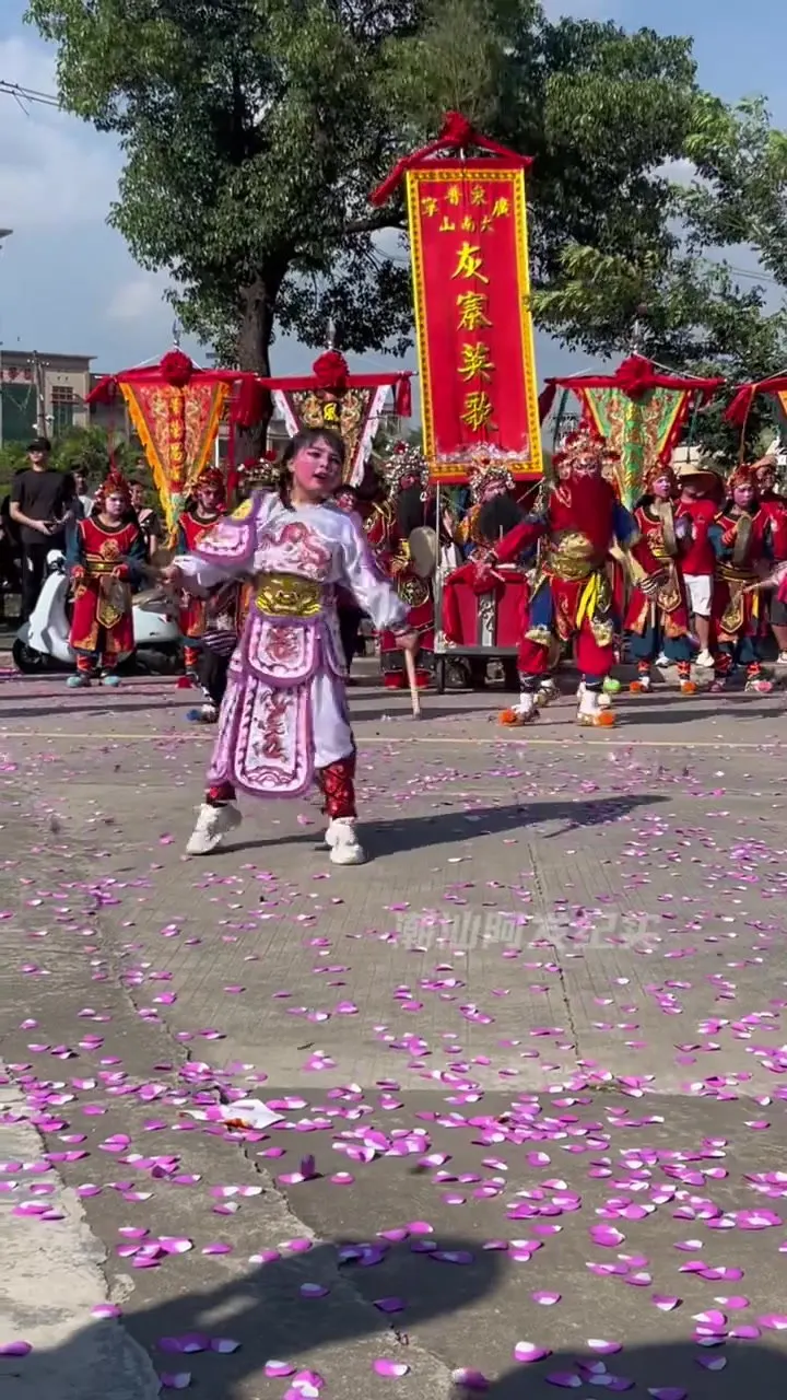 灰寨英歌队在场地前列队,队前一名小队员,后方举「灰寨英歌」竖标旗