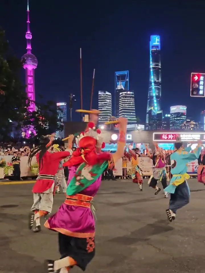 上海外滩夜景，英歌队在街道上演出，围栏外是举手机的观众