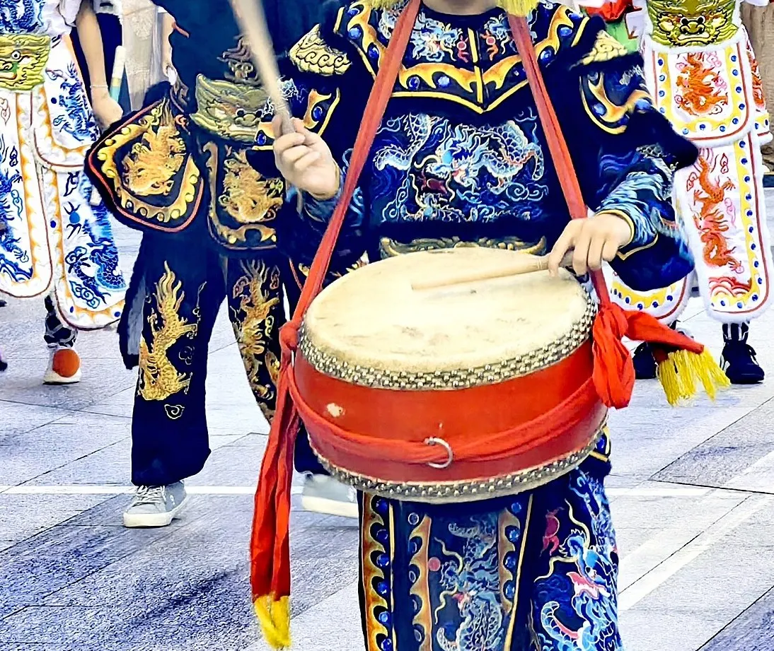 鼓手斜挎一面大圆鼓,鼓身漆红,鼓面米白,右手一根木鼓槌