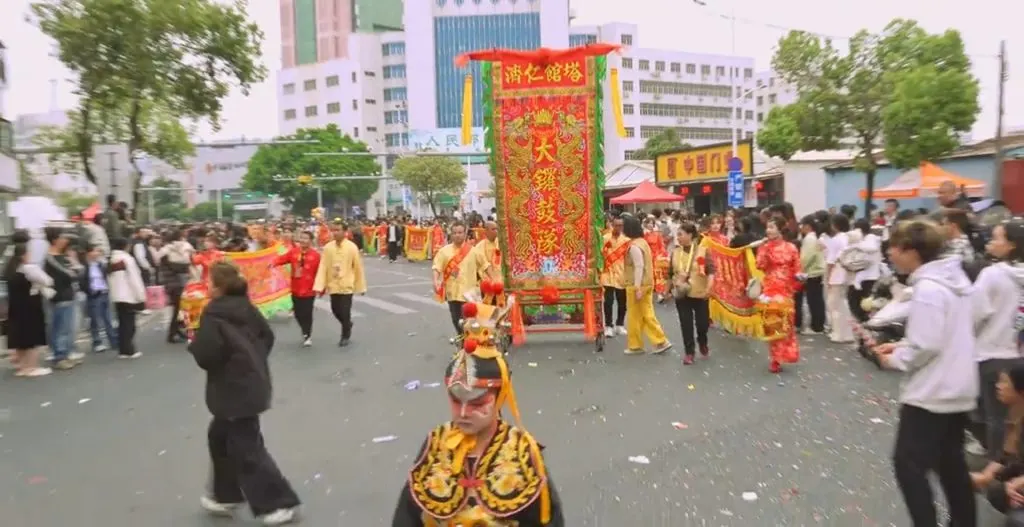 巡遊隊伍在街心走過，兩側是商鋪與行人