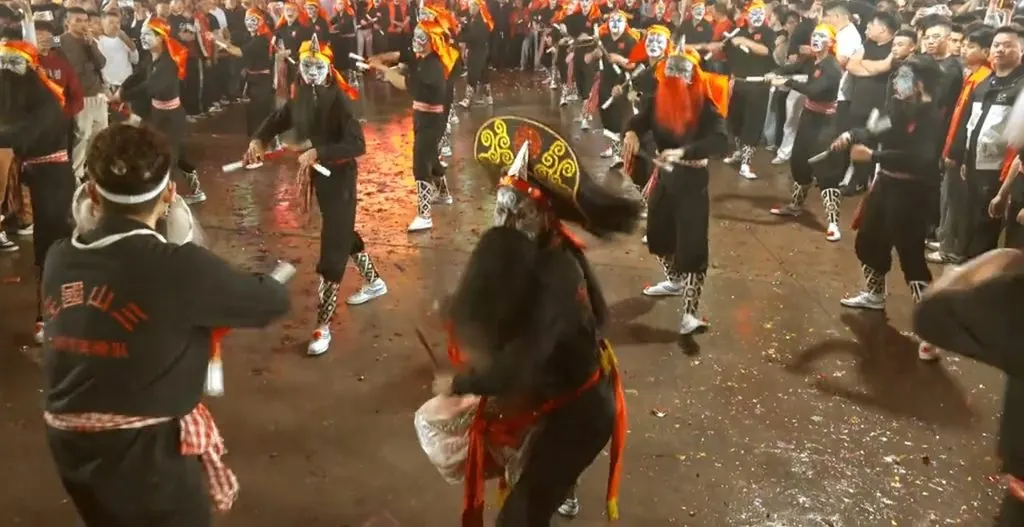 夜裡滿場隊員舉槌相向，近處一人背對鏡頭，衫上印「三山國王」