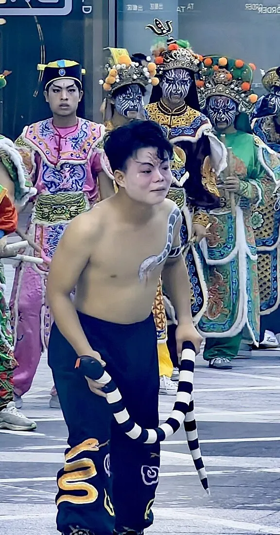 赤膊的队员手里一条黑白条纹布蛇,黑裤腿上绣着金蛇